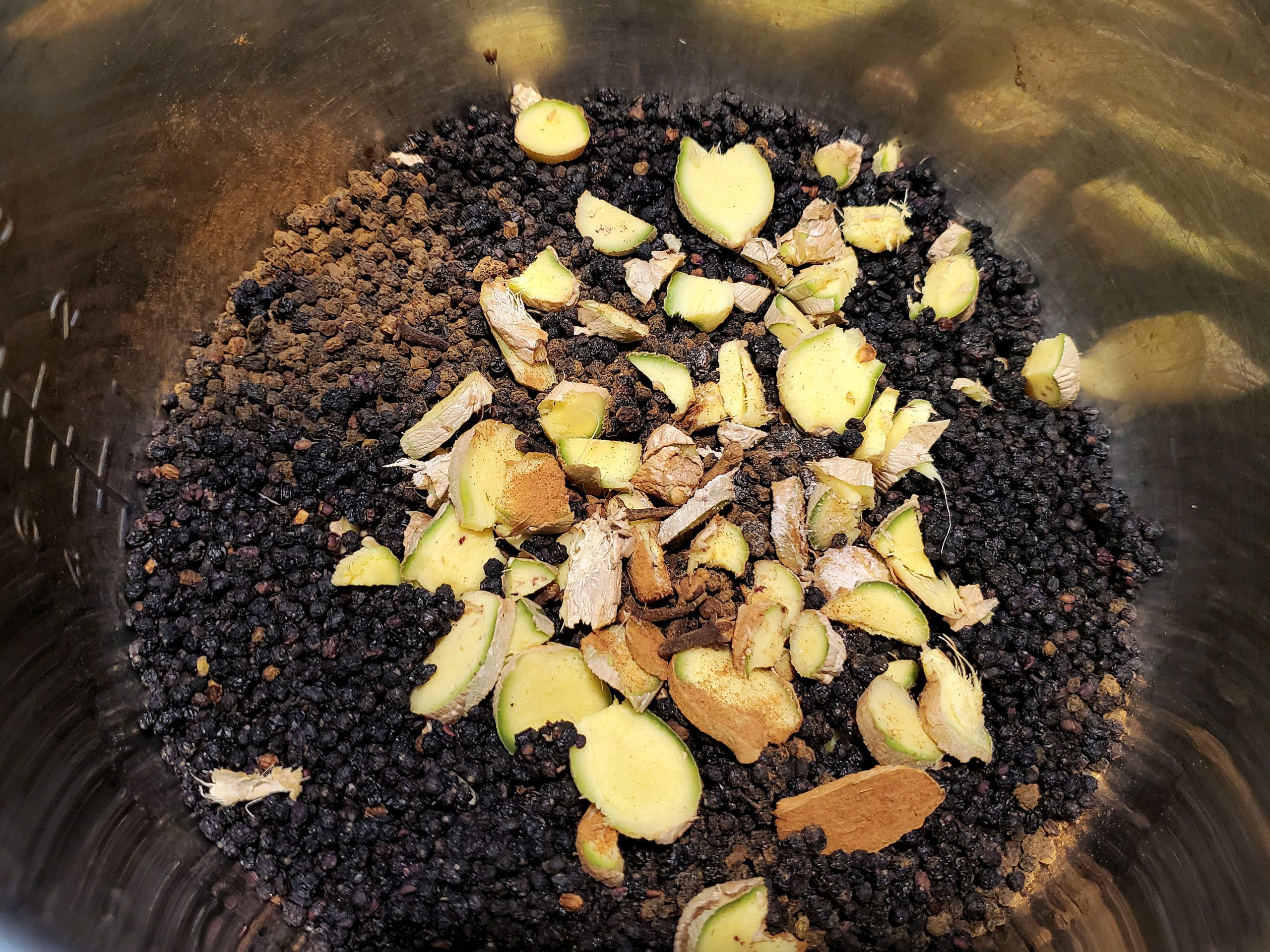Dried elderberries, ginger, and spices in pot